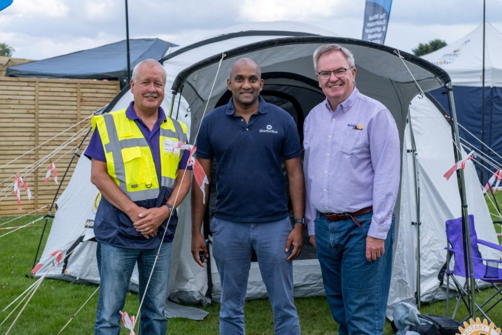 Three men standing in front of a ShelterBox tent