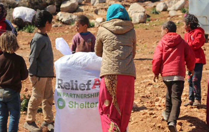 Women and children with bag of aid from ReliefAid and ShelterBox in Syria
