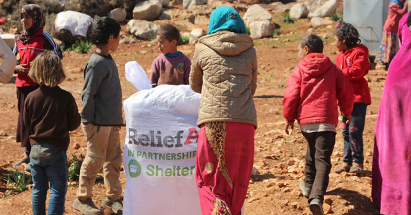 Women and children with bag of aid from ReliefAid and ShelterBox in Syria