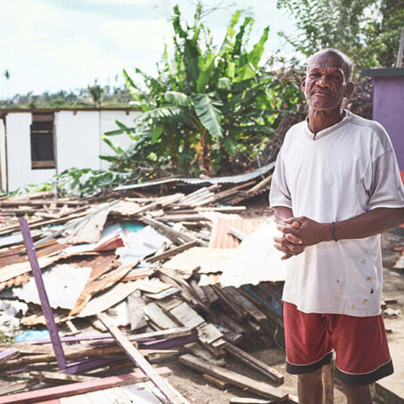 Man in the Caribbean standing amongst rubble.