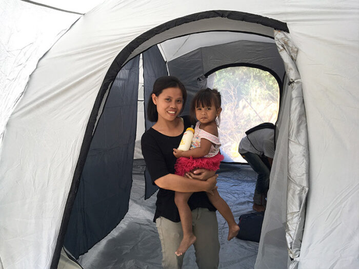 A woman carrying her daughter inside a tent