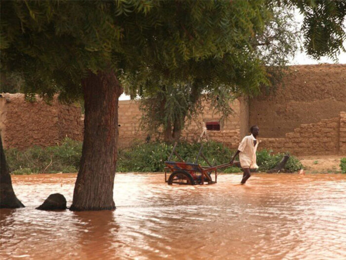 Young man pulls cart through floodwaters in Niger