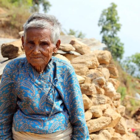 A lady in Nepal sitting beside a mountain of rocks