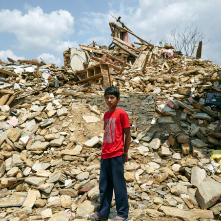 A boy in Nepal standing at the bottom of a mountain of building debris
