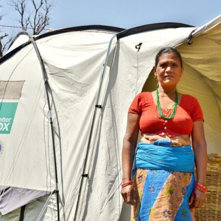 Nepalese lady standing in front of her Shelterbox home