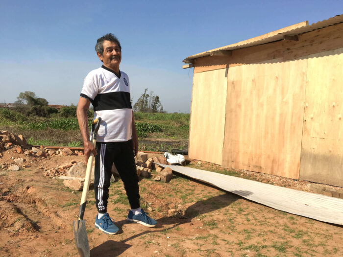 A man with a shovel outside his wooden shelter in Paraguay