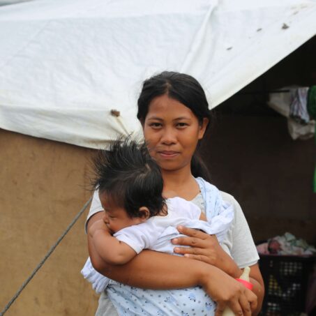 Woman carrying child in front of shelter