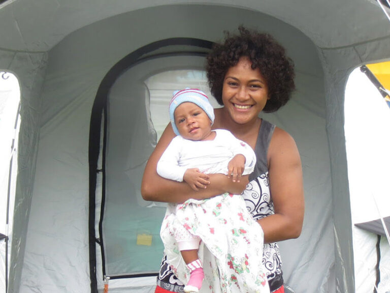 Woman with child standing in front of ShelterBox tent