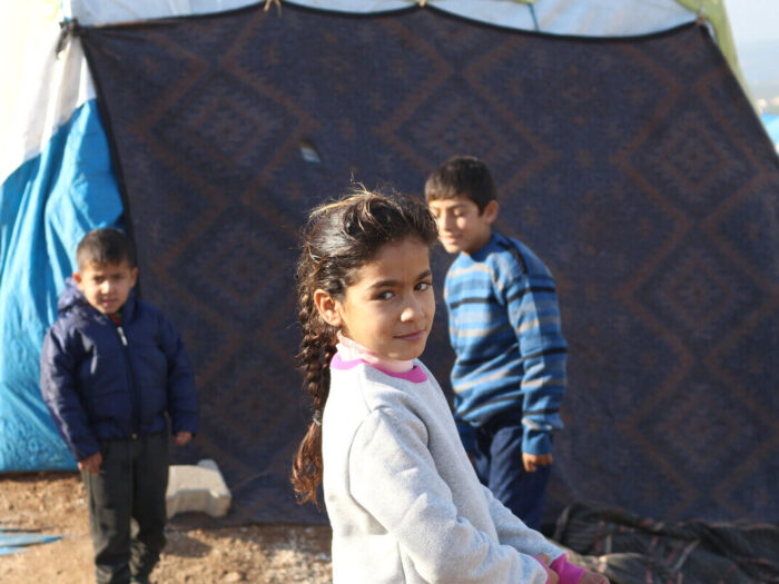 children playing outside their tent at a refugee camp in Syria