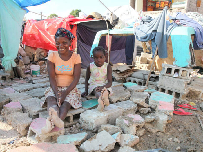 Woman and child sit amongst rubble