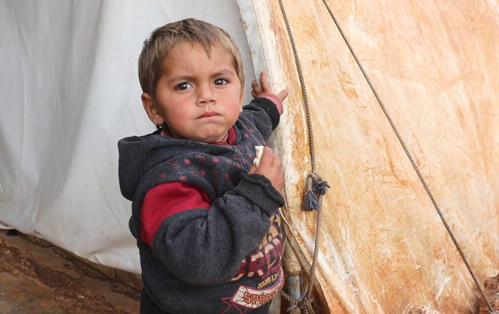 Little boy next to tent in Syria