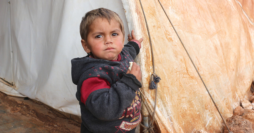 Little boy next to tent in Syria