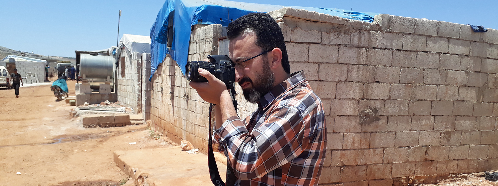 man holding a camera in a Syrian refugee camp