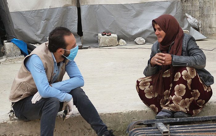 Man wearing facemask talking to a woman in Syria
