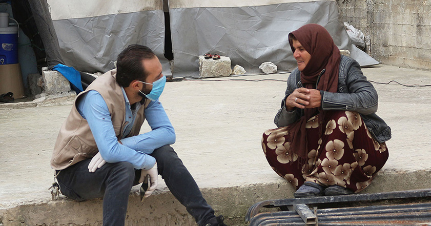 Man wearing facemask talking to a woman in Syria