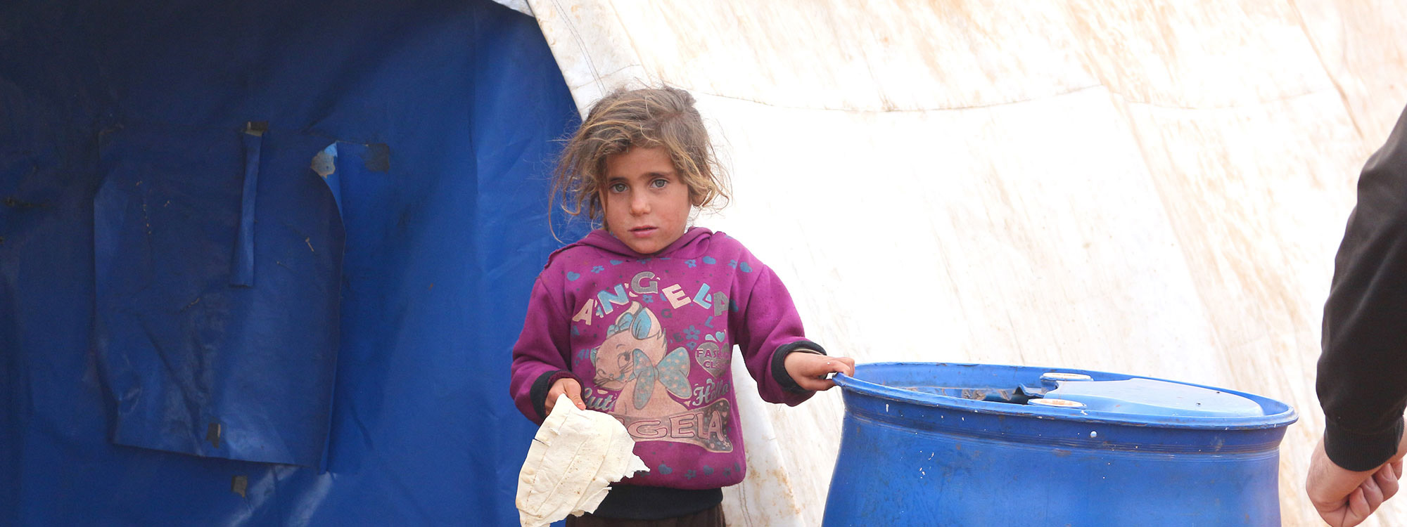 Little girl standing outside a tent in Syria