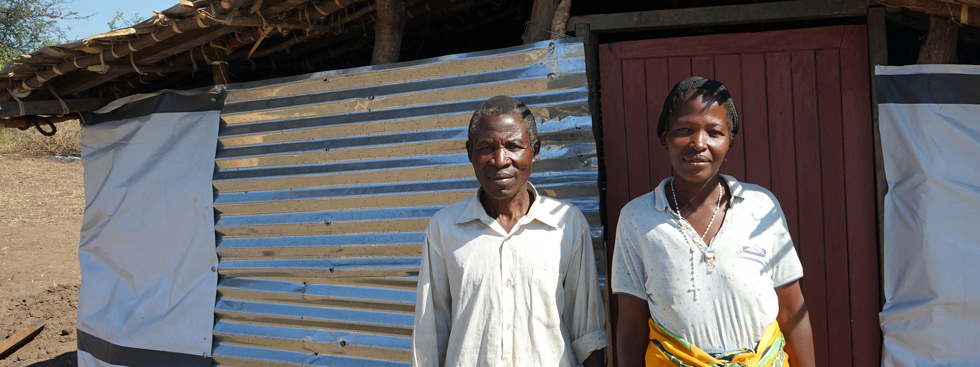 Couple standing outside their home in Malawi