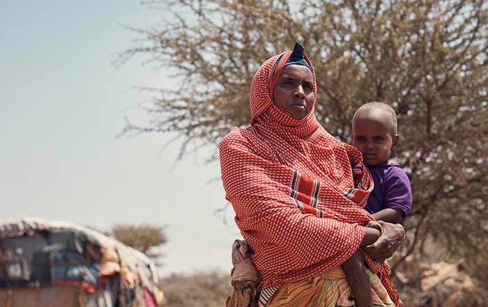 Woman wearing a red and white head scarf holding a child in Somaliland