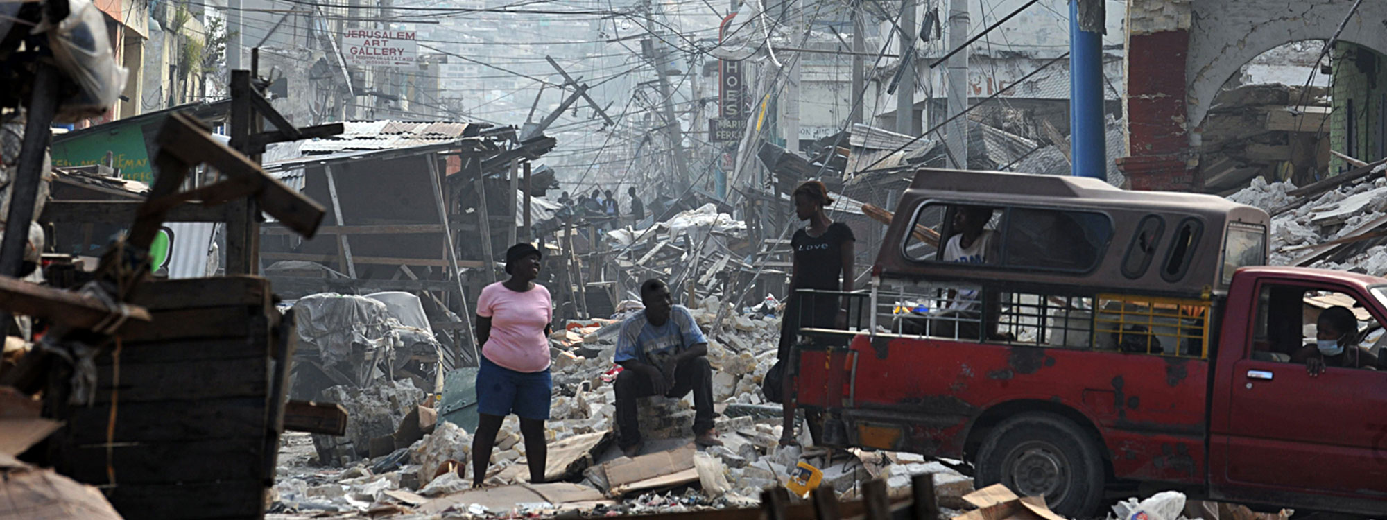 people standing amongst destroyed buildings after haiti earthquake