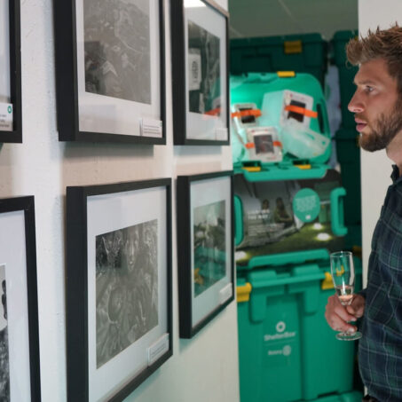 Man looking at framed photographs on a wall in the ShelterBox Visitor Centre