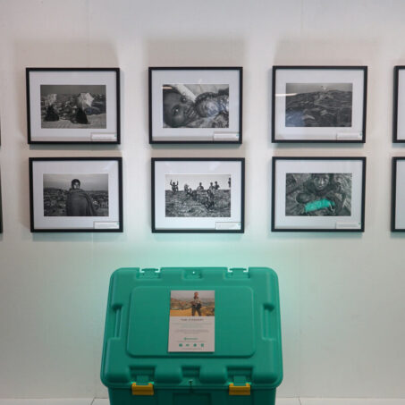 Framed photographs on a wall above a green box in the ShelterBox visitor centre