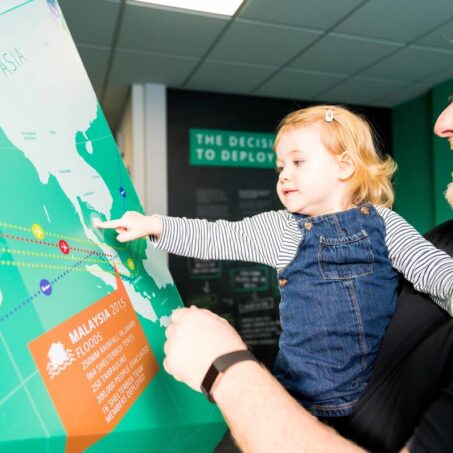 Man holding child pointing at map in ShelterBox visitor centre