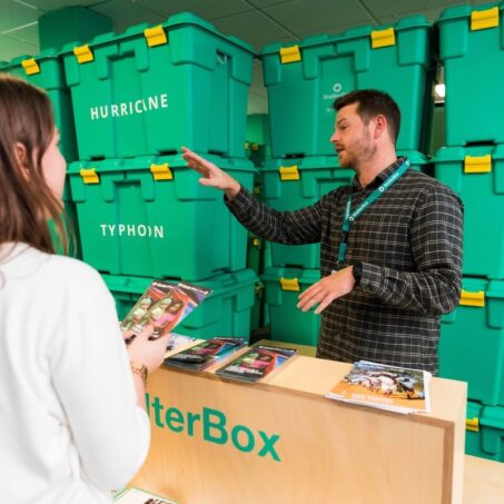Person in front of stack of green boxes in the ShelterBox visitor centre