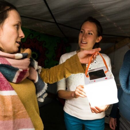 3 adults holding solar light in the ShelterBox visitor centre