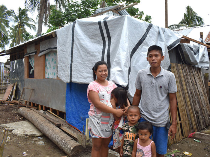 A Filipino family of 5 posing outside their damaged home