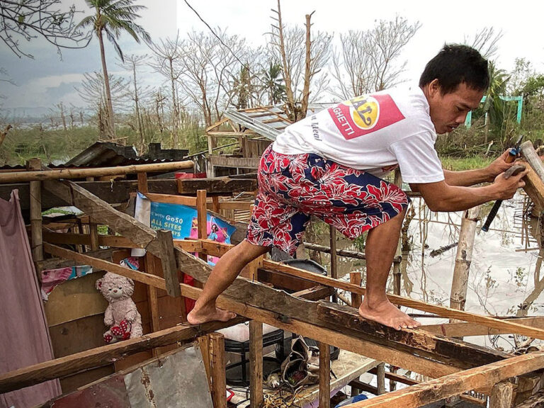 Man on a damaged roof after typhoon Goni Philippines