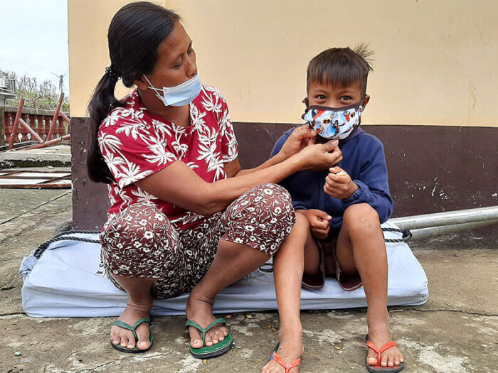 mother adjusts son's facemask in philippines