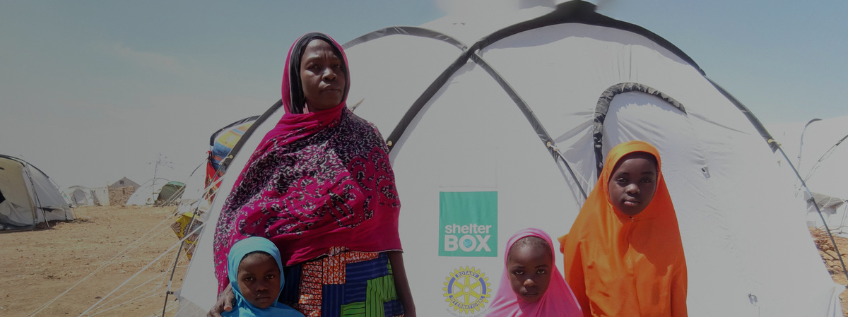 A woman standing in front of a tent with three children around her