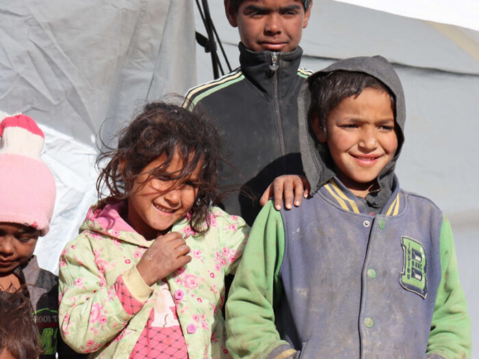 3 children smiling in front of a tent