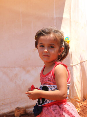 girl wearing a red top at a Syrian camp