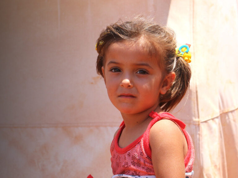 girl wearing a red top at a Syrian camp