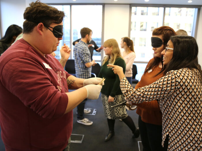 Group of people, some wearing blindfolds, at a training event