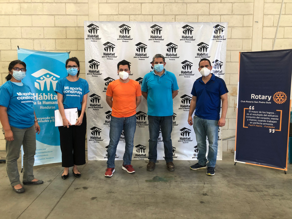 Team members from Rotary International and Habitat for Humanity standing in front of a display board
