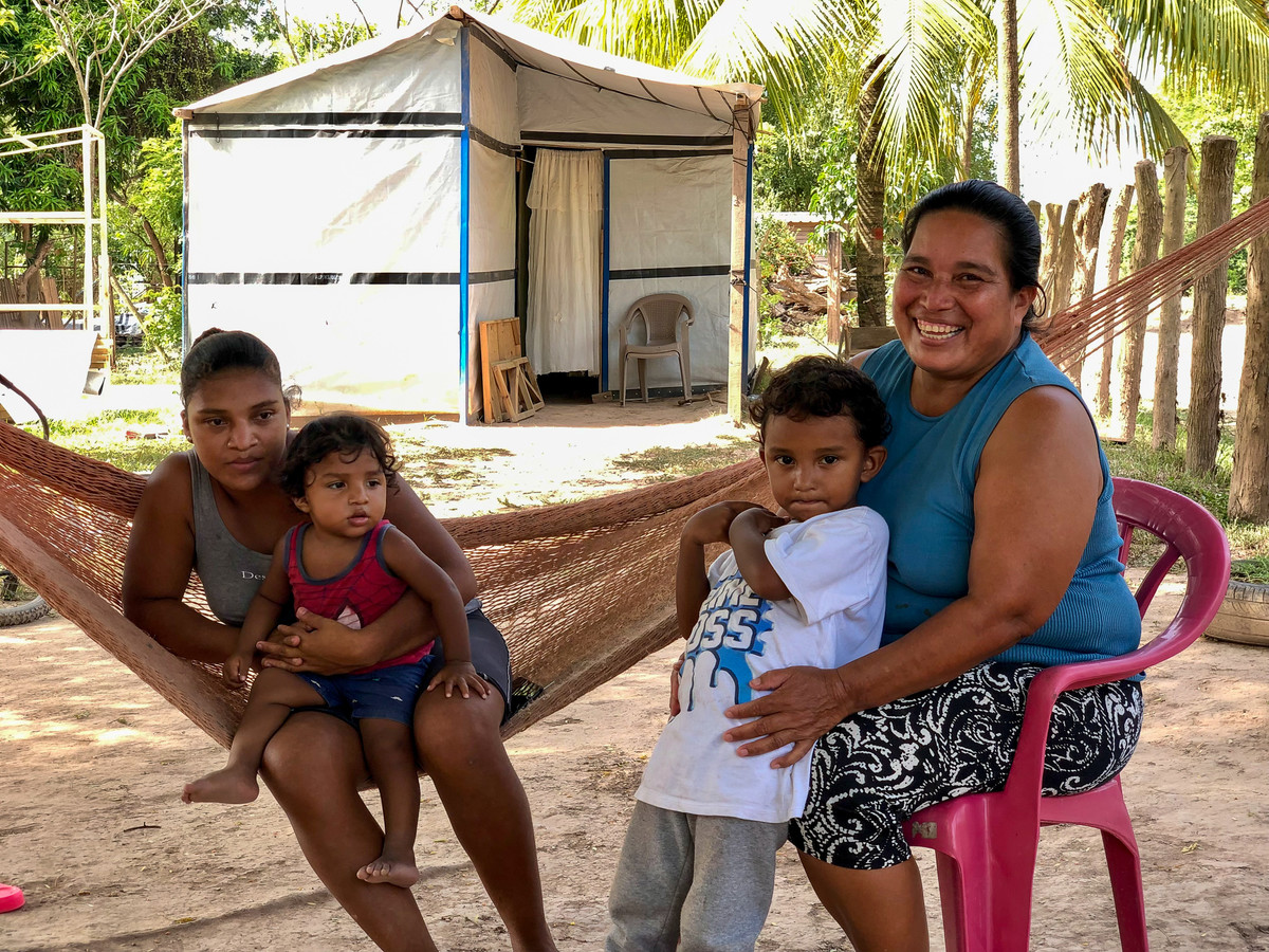 A woman and three children sat in front of a repaired shelter in Honduras after Hurricanes Eta and Iota