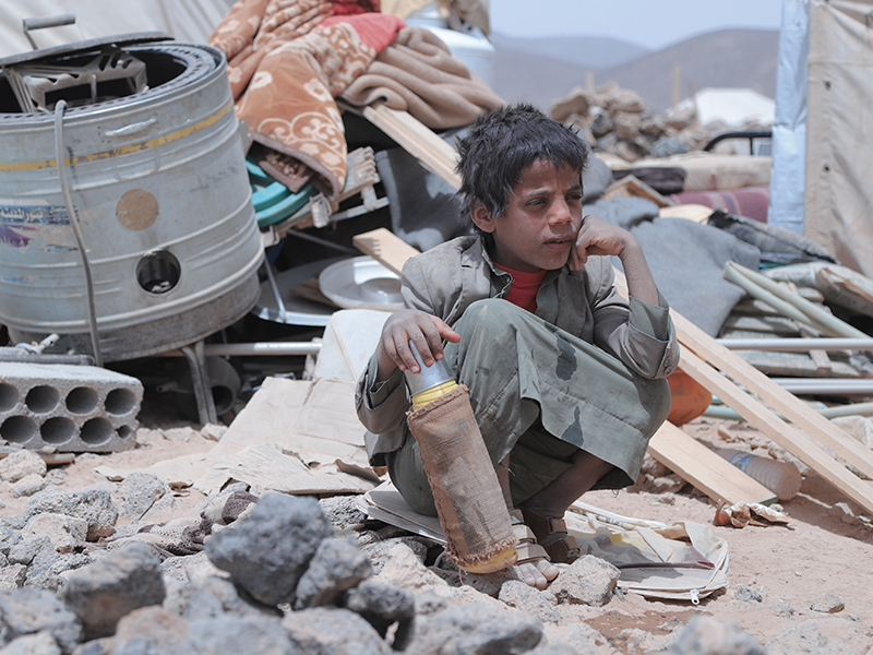 Boy squatting around rubble in Yemen