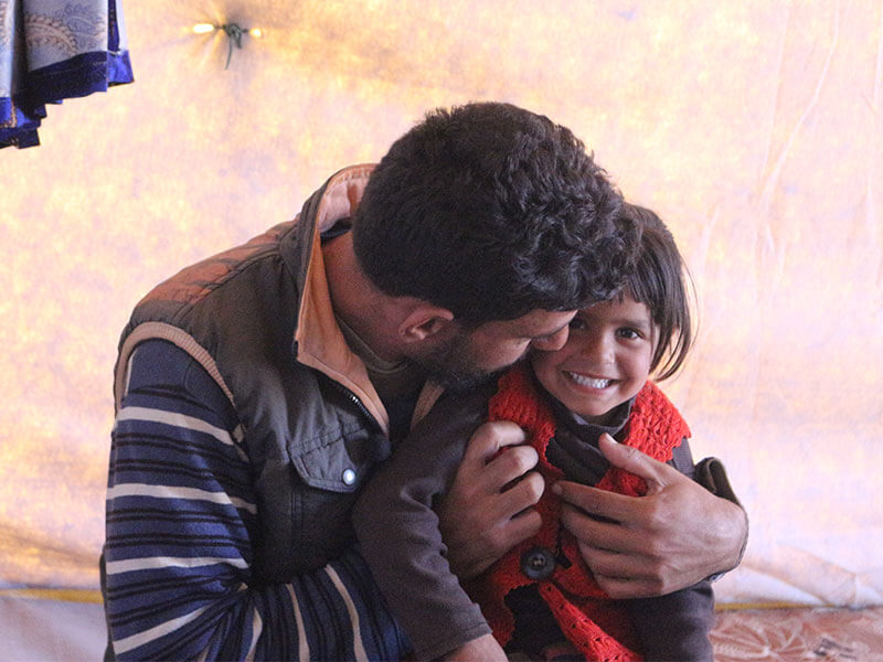 man hugs daughter in tent insyria