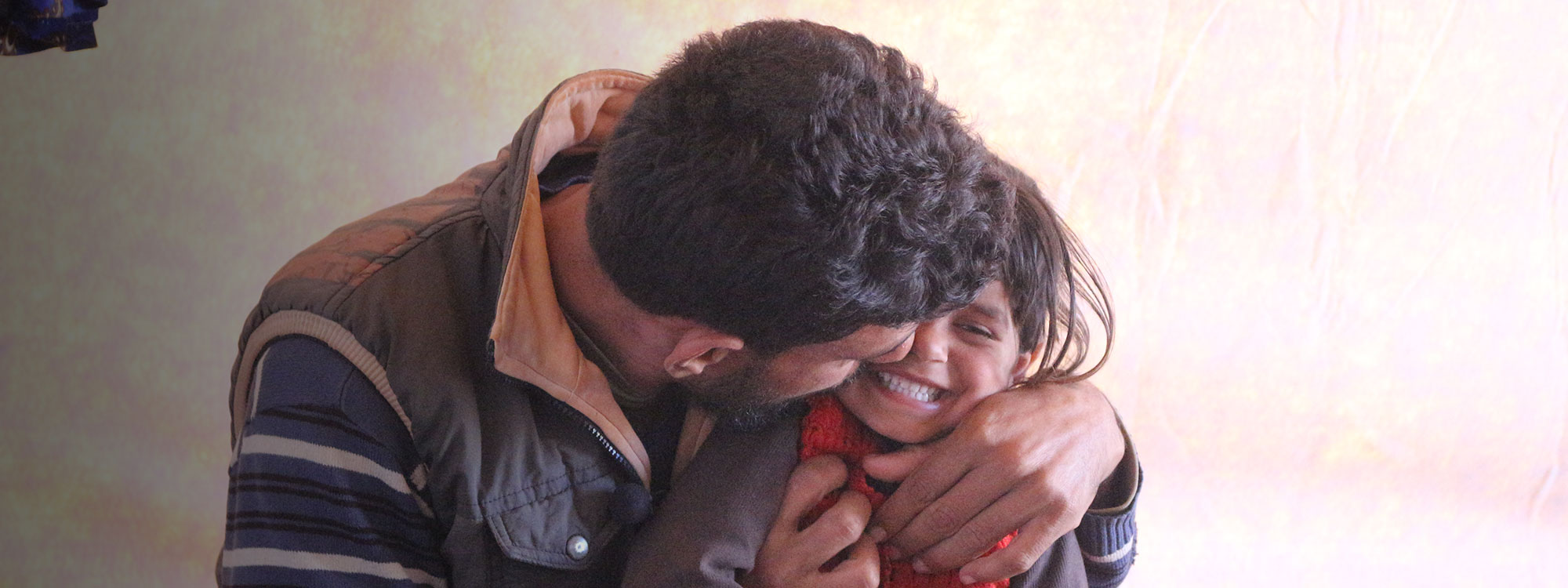 man laughing hugging daughter in Syria