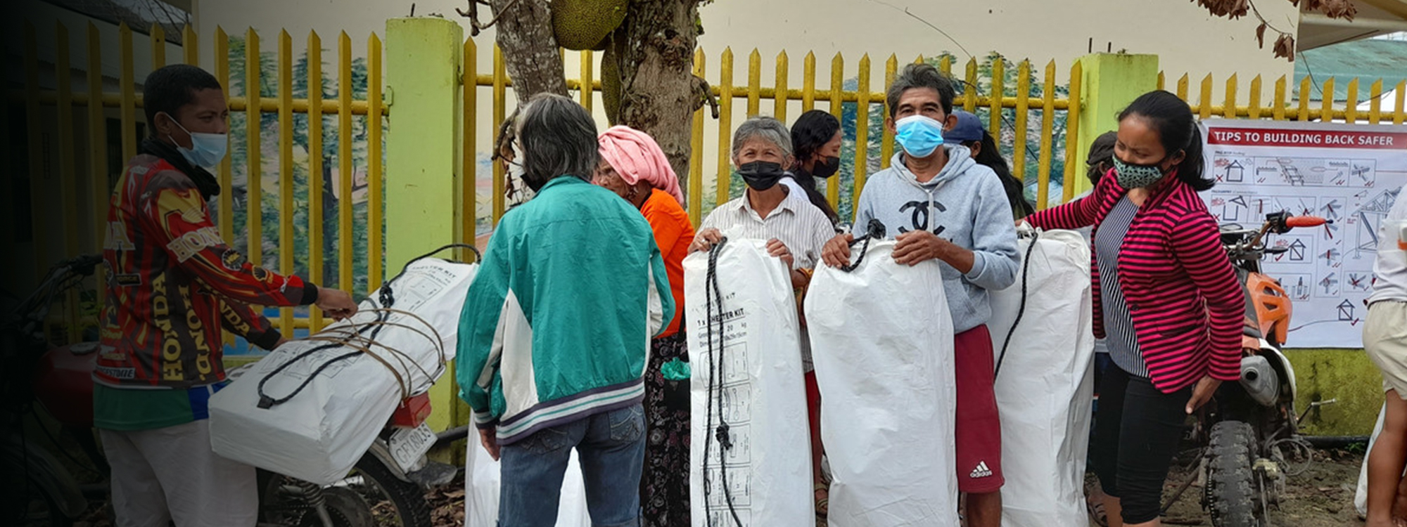 People wearing masks and receiving shelter kits