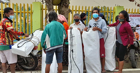 People wearing masks and receiving shelter kits