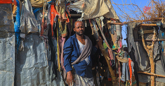 Yemeni man standing in front of shelter