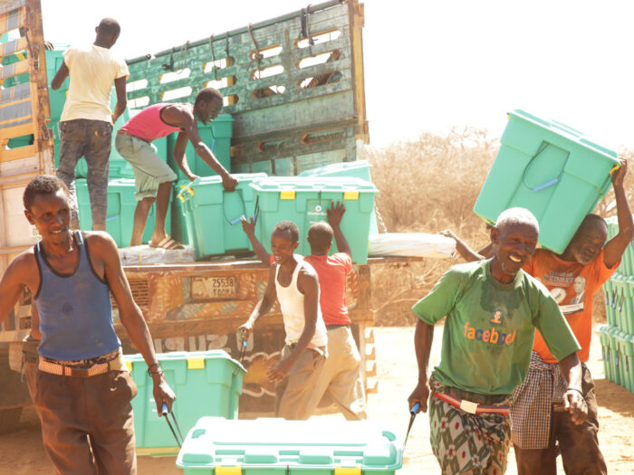 People unloading green boxes off a truck