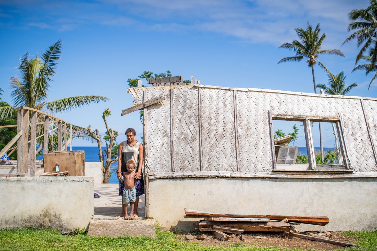 woman and child stand in destroyed home after extreme storm Cyclone Harold hit Vanuatu