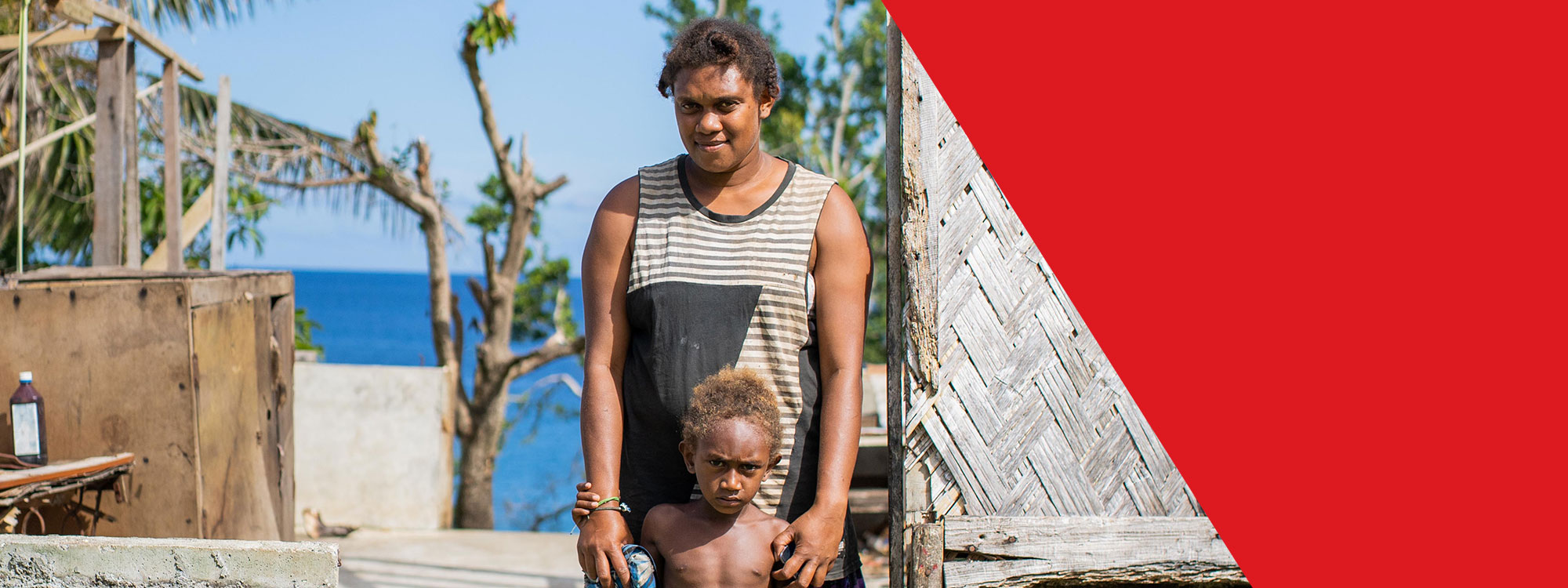 mother and child standing outside destroyed home in vanuatu