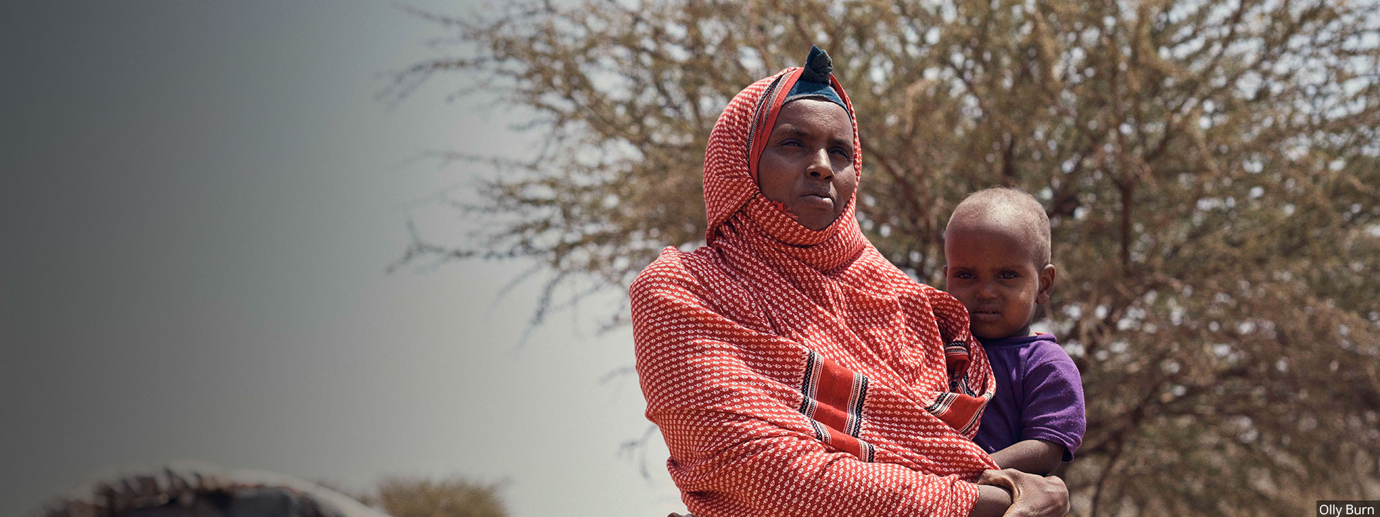 Somaliland woman in red headscarf holding child by olly burn