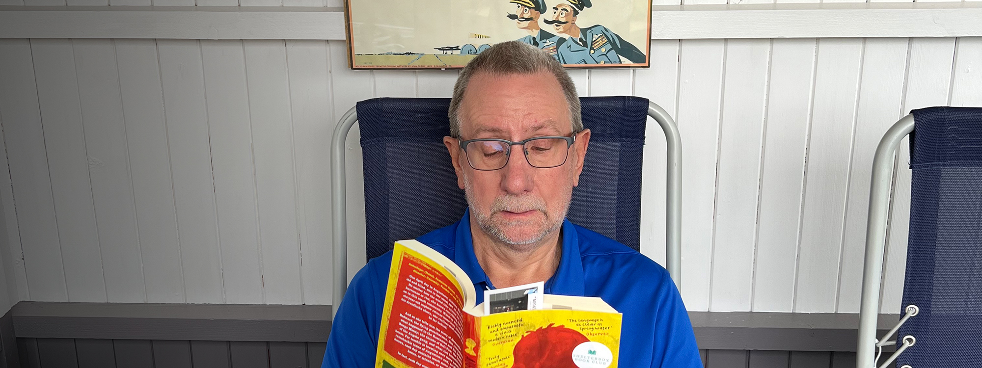 Author Brian Stewart sitting and reading a book from the ShelterBox book club