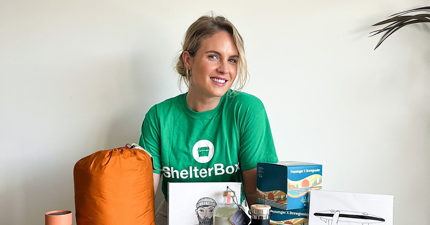 Women wearing ShelterBox t shirt next to table with items on it